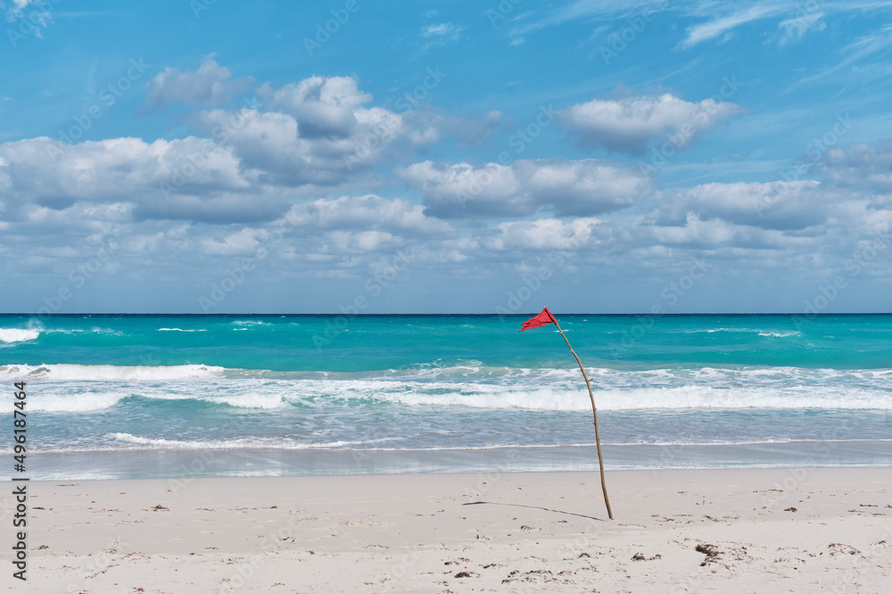 Red flag on sandy beach of Atlantic Ocean, Varadero, Cuba. Danger sign,  swimming is prohibited. Photos | Adobe Stock