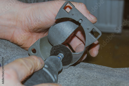 The hands of a man holding a Dremel instrument.Metalworking. Workshop. Production of products. Carpentry cutting tool.Car tuning and repair.Using a Dremel to cut out a metal part. photo