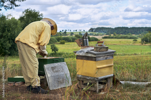 Pszczelarz przy ulach w swojej pasiece. Ocenia wiosną, jak roje pszczół przetrwały zimę.