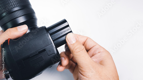 Photographer hand installing lithium ion battery of digital DSLR cameras,isolated on white background with copy space