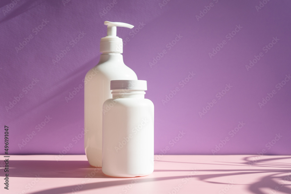white cosmetic jars on a lilac-pink background with sun shadows. template for cosmetics. white cosmetic jars on a lilac-pink background with sun shadows. template for cosmetics.