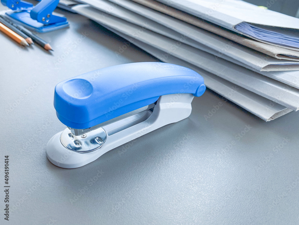 Photo of blue stapler put on the table in office, stapler is a device used in schools or offices - obrazy, fototapety, plakaty 