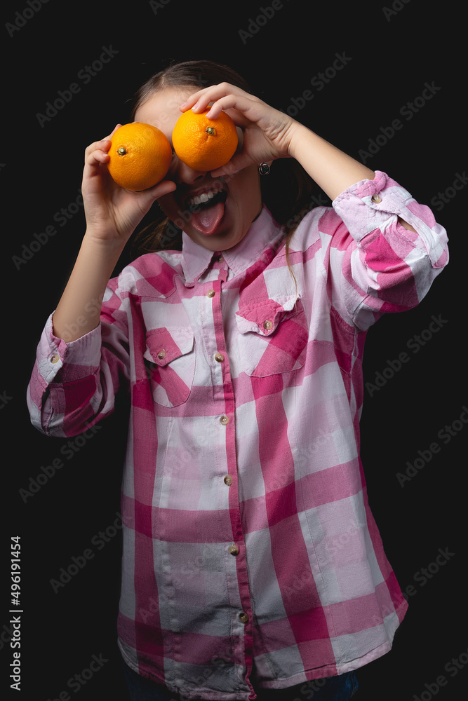 Little cute girl with tangerines posing in the studio on a black background. Little cute girl with tangerines posing in the studio on a black background.