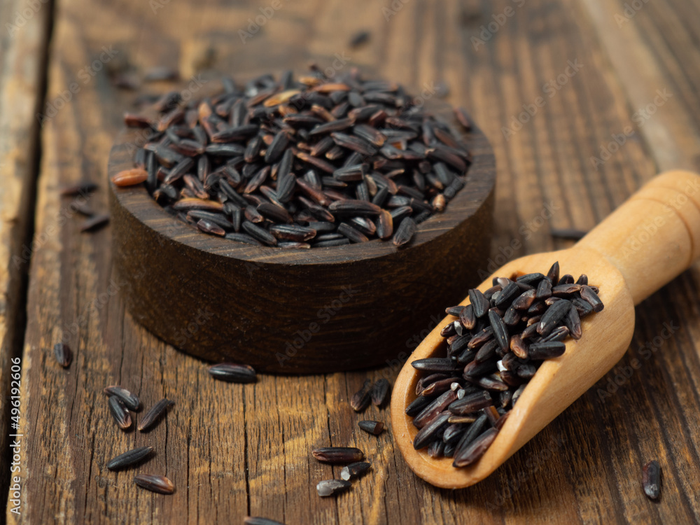 pile of black rice in a wooden bowl on a wooden table close-up pile of black rice in a wooden bowl on a wooden table close-up