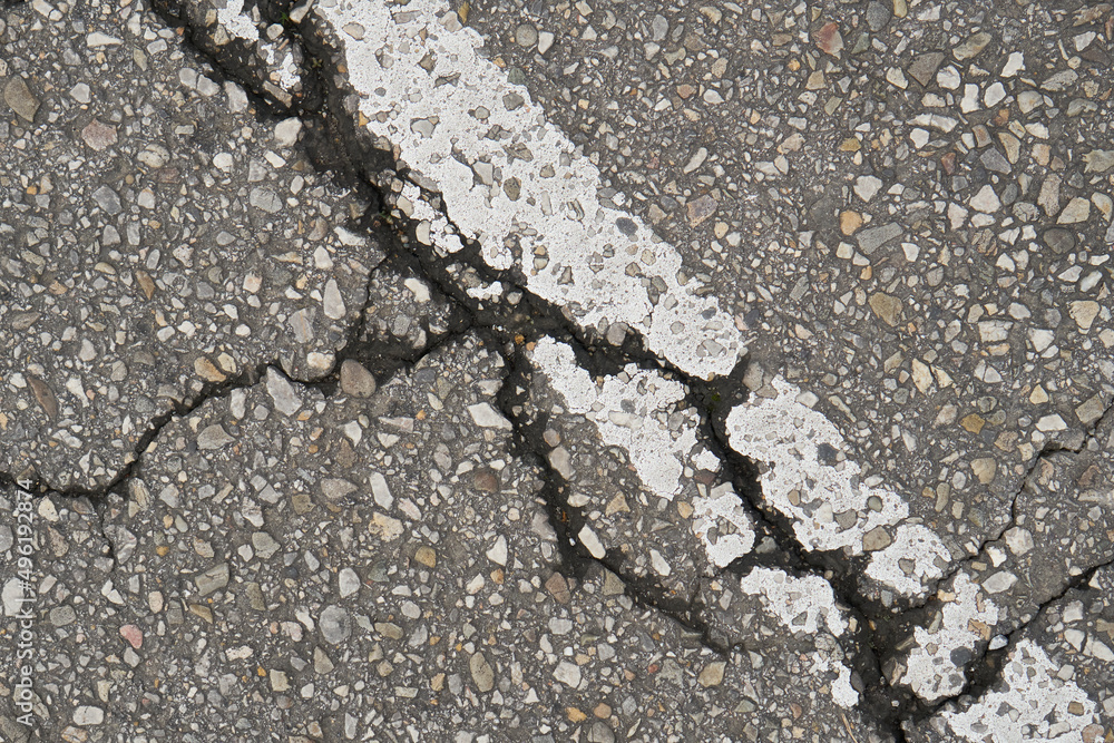 Old damaged cracked asphalt road section with old paint road marking. Texture damage. Deterioration of the road surface Old damaged cracked asphalt road section with old paint road marking. Texture damage. Deterioration of the road surface