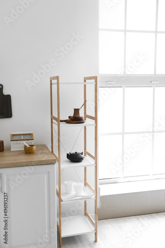 Shelf unit with kitchenware near white wall © Pixel-Shot