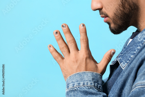 Concentrated man with stylish manicure on color background, closeup