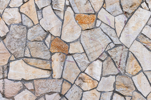 Old stone wall of stones of different sizes and colors as a natural background
