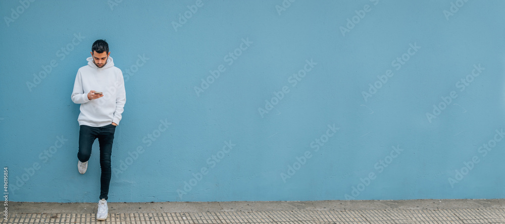 Fototapeta premium young man with mobile phone on the street wall