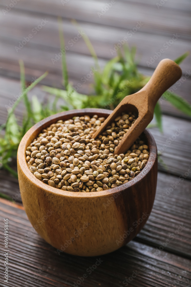Bowl and scoop with hemp seeds on wooden background Bowl and scoop with hemp seeds on wooden background
