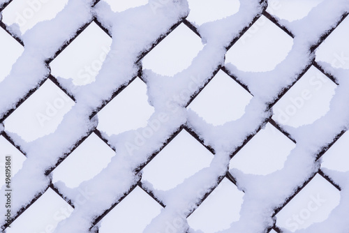 The fence is covered in snow. Snow sticking to a metal fence.