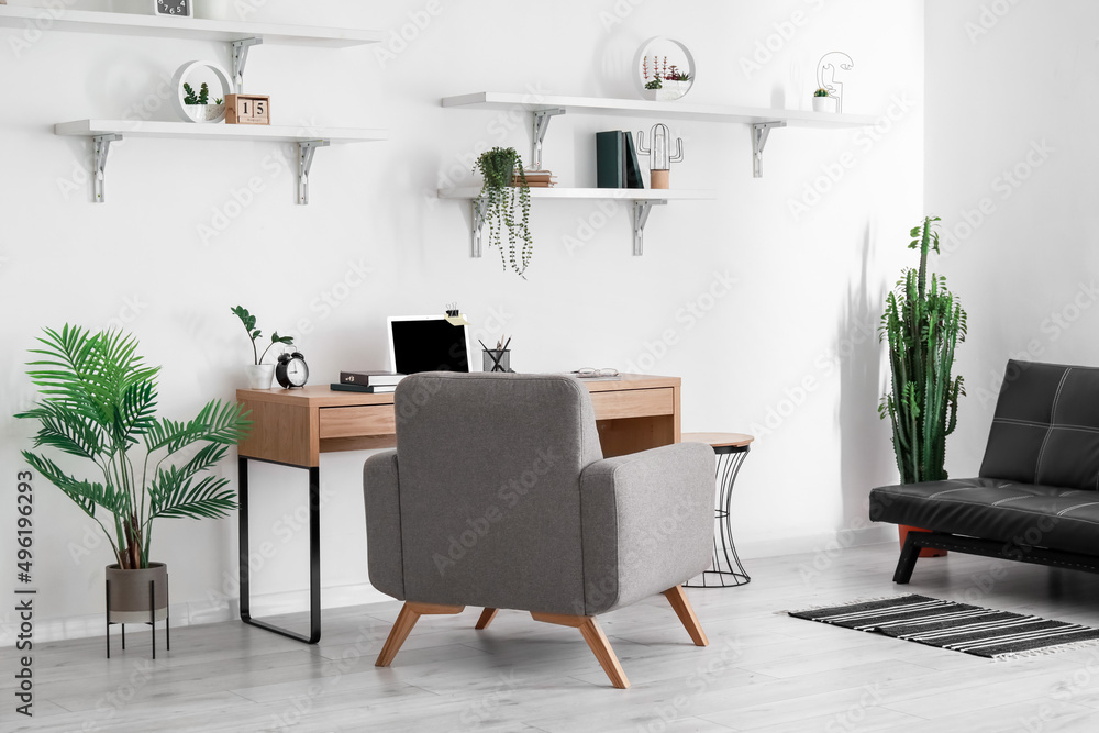 Fototapeta premium Comfortable workplace and houseplants in stylish room interior