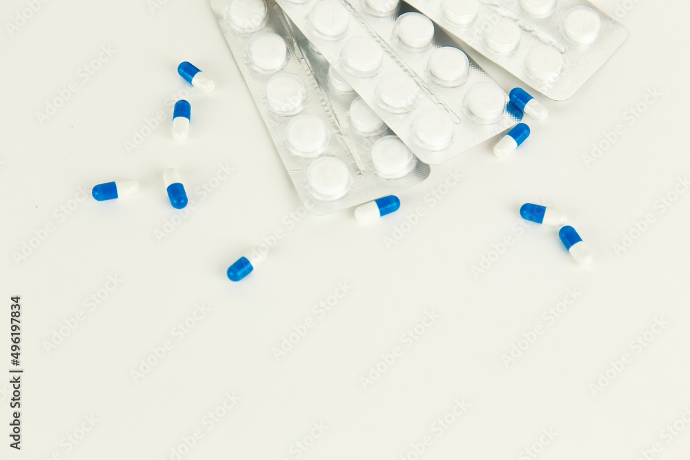 falling blue pills on pile of capsules on white background falling blue pills on pile of capsules on white background