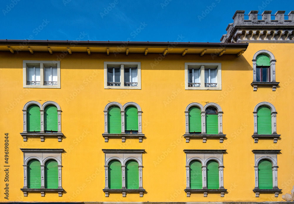 A well kept old yellow building with green shutters A well kept old yellow building with green shutters