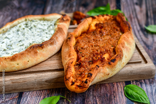  Traditional Turkish cuisine. Baked Pide dish with  cheese and  herbs on  wooden background.  Turkish pizza pide
