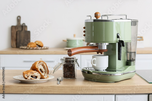 Modern coffee machine, jar of beans and croissant on counter in kitchen © Pixel-Shot