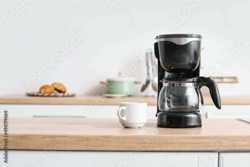 Black coffee machine with cup on counter in kitchen