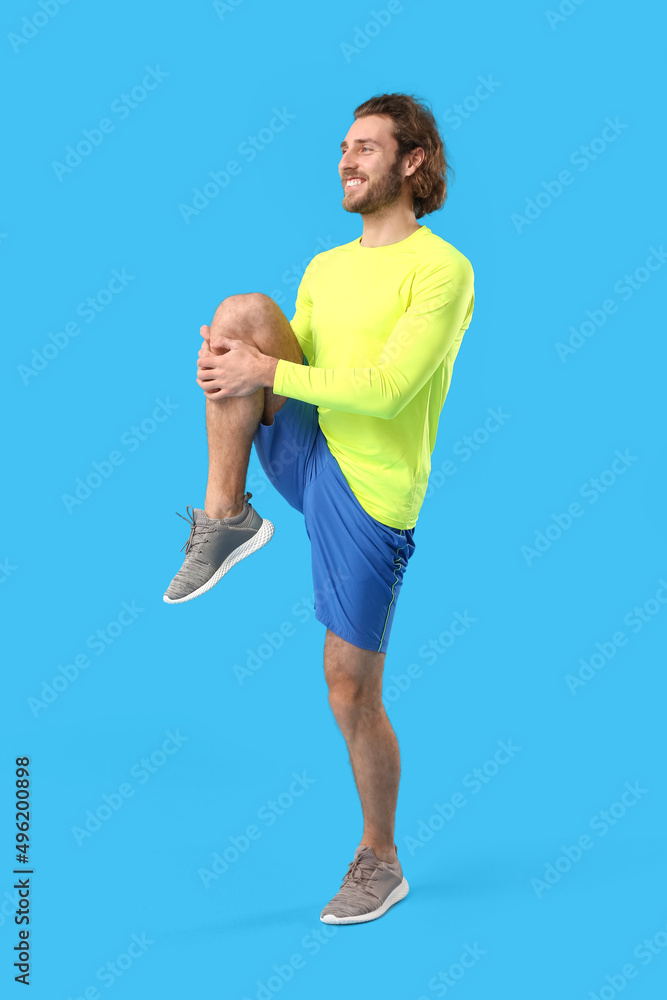 Sporty man stretching on blue background