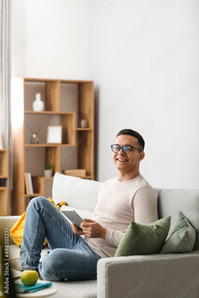 Male student using tablet computer on sofa at home Male student using tablet computer on sofa at home