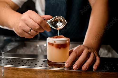 Bartender use measure spoon and add brown syrup to cocktail in glass