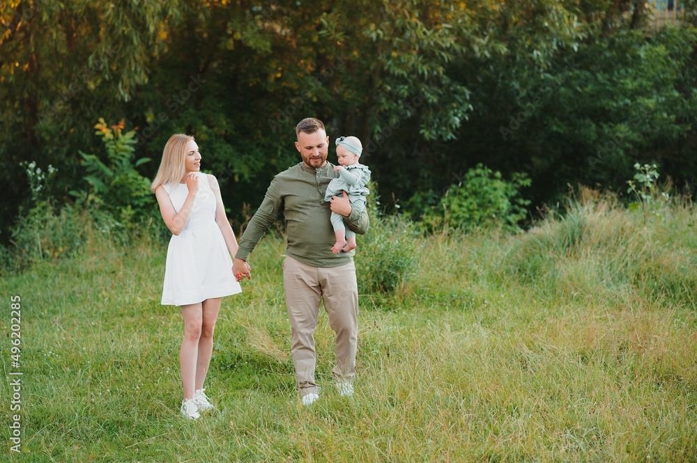 Young beautiful family with a little daughter hug, kiss and walk in nature at sunset. Photo of a family with a small child in nature. Young beautiful family with a little daughter hug, kiss and walk in nature at sunset. Photo of a family with a small child in nature.