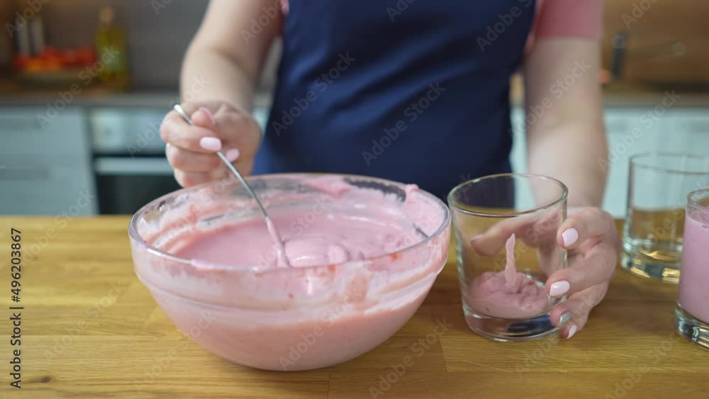 transfers strawberry pudding to serving glasses. close up transfers strawberry pudding to serving glasses. close up