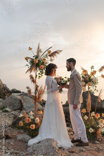 Wedding on the sunset with live floristry. Bride and groom in boho style. 