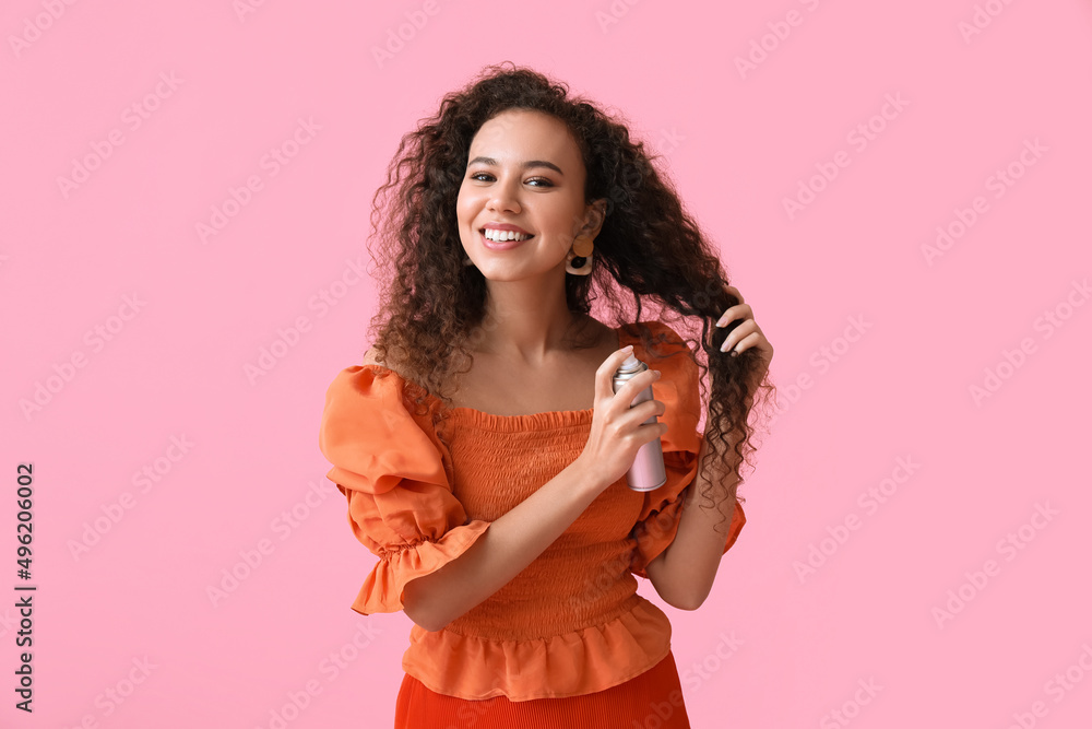Pretty young African-American woman with hair spray on pink background Pretty young African-American woman with hair spray on pink background