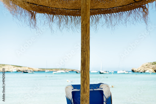 Sun lounger under an straw umbrella on the beach