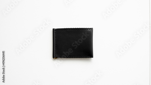 Black men's money clip handmade leather wallet. Empty money clip wallet with a two pockets for cards lies on a white table. Selective focus, copy space.