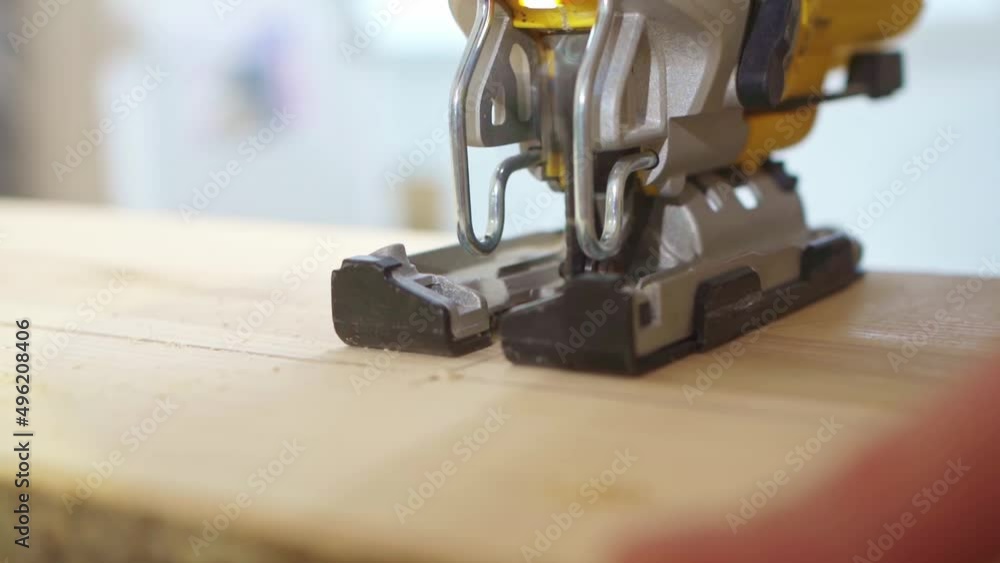 carpenter cuts wood with electric jigsaw