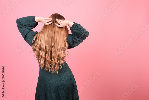 Girl on a pink background with gorgeous long hair, hair care. Brunette, redhead model with curled hair