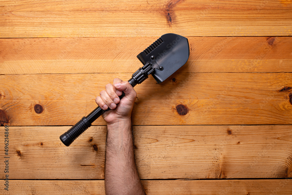 hand grabbing shovel on light wooden background - Labor Day