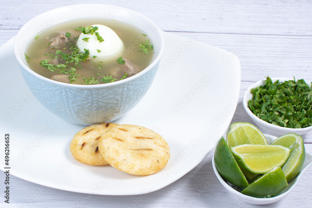 Chicken consomme, traditional Colombian food, accompanied by hard-boiled egg, corn arepas, cilantro and lemon Chicken consomme, traditional Colombian food, accompanied by hard-boiled egg, corn arepas, cilantro and lemon