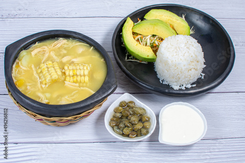 Ajiaco, traditional Colombian food, accompanied by rice, milk cream, avocado, capers and salad