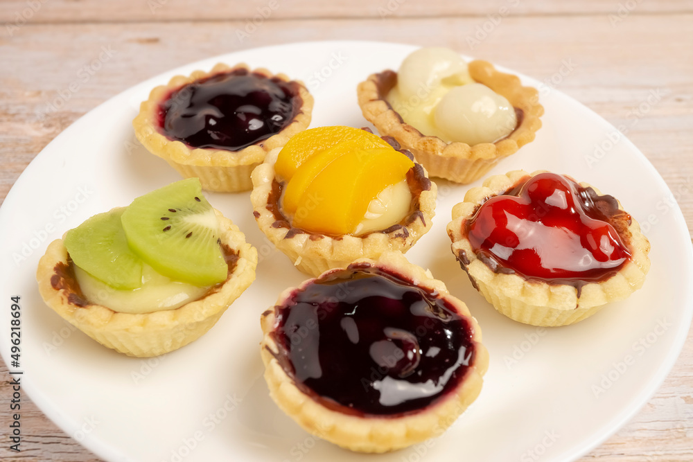 Homemade Fruits tarts, Sweet desserts topping with fresh kiwi, blueberries, peach, longan, raspberries in syrup, on wooden table.
Homemade Fruits tarts, Sweet desserts topping with fresh kiwi, blueberries, peach, longan, raspberries in syrup, on wooden table.