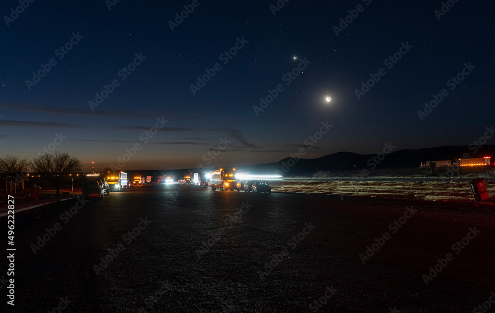 Cars and semi trucks parked at a highway rest area at dawn