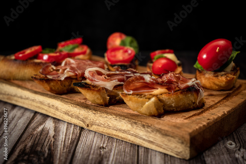 Arrangement of a selection of different tapas or bruschettas on a wooden board. Mediterranean food concept.