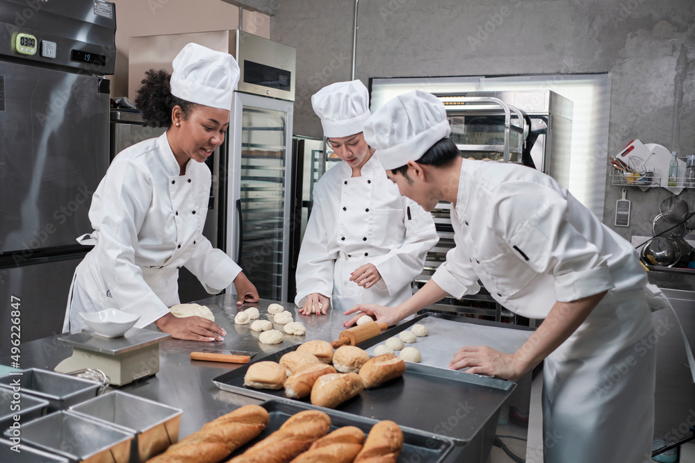 Professional gourmet team, three young chefs in white cook uniforms and