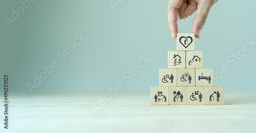 Elderly care concept. Hand holds wooden cubes with icons related to elderly care, medical, rehabilitation service, nursing care for enhancing quality of life in elder age. Used for banner, background.