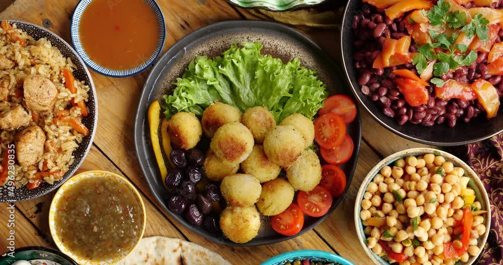 Falafel balls made from ground chickpeas is eaten throughout the Middle East and is a common street food. Women's hands serve a table for iftar dinner during Ramadan Falafel balls made from ground chickpeas is eaten throughout the Middle East and is a common street food. Women's hands serve a table for iftar dinner during Ramadan