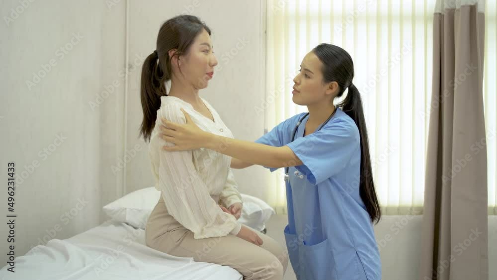 Young asian female doctor treating woman patient with back pain, Female physiotherapist touch on back for checking backbone injury, and listening to her patient's back with a stethoscope Young asian female doctor treating woman patient with back pain, Female physiotherapist touch on back for checking backbone injury, and listening to her patient's back with a stethoscope