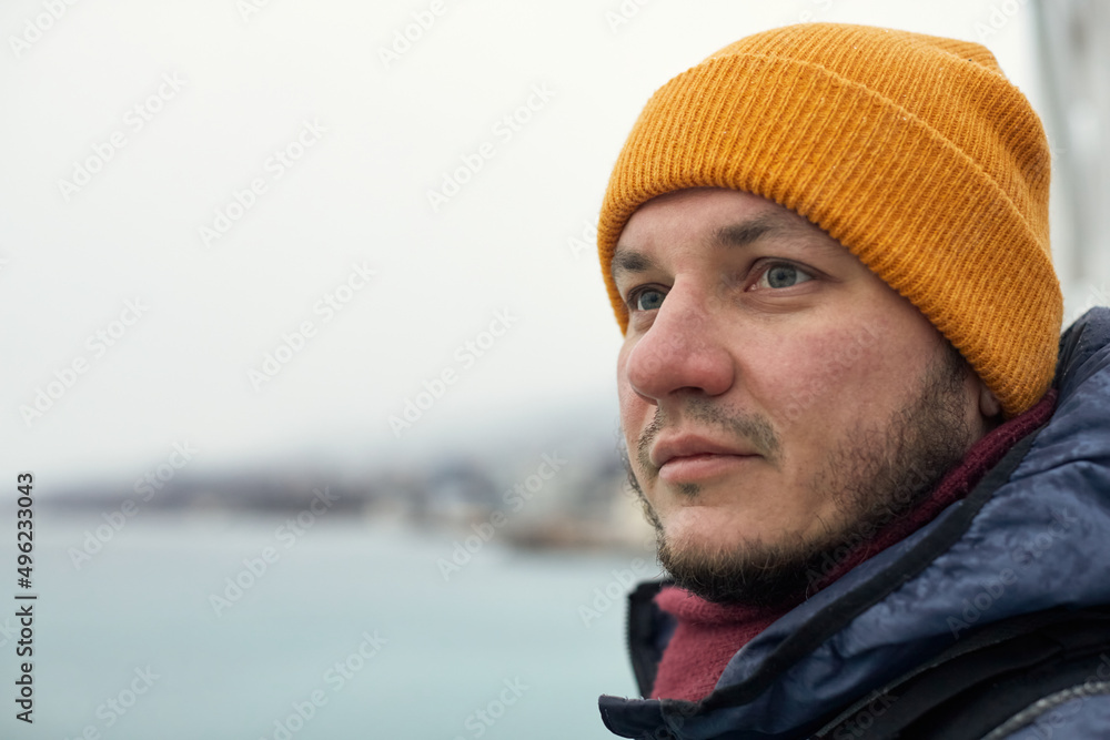 A man in winter clothes by the sea looks into the distance. The concept of travel, winter holidays. Front view. A man in winter clothes by the sea looks into the distance. The concept of travel, winter holidays. Front view.