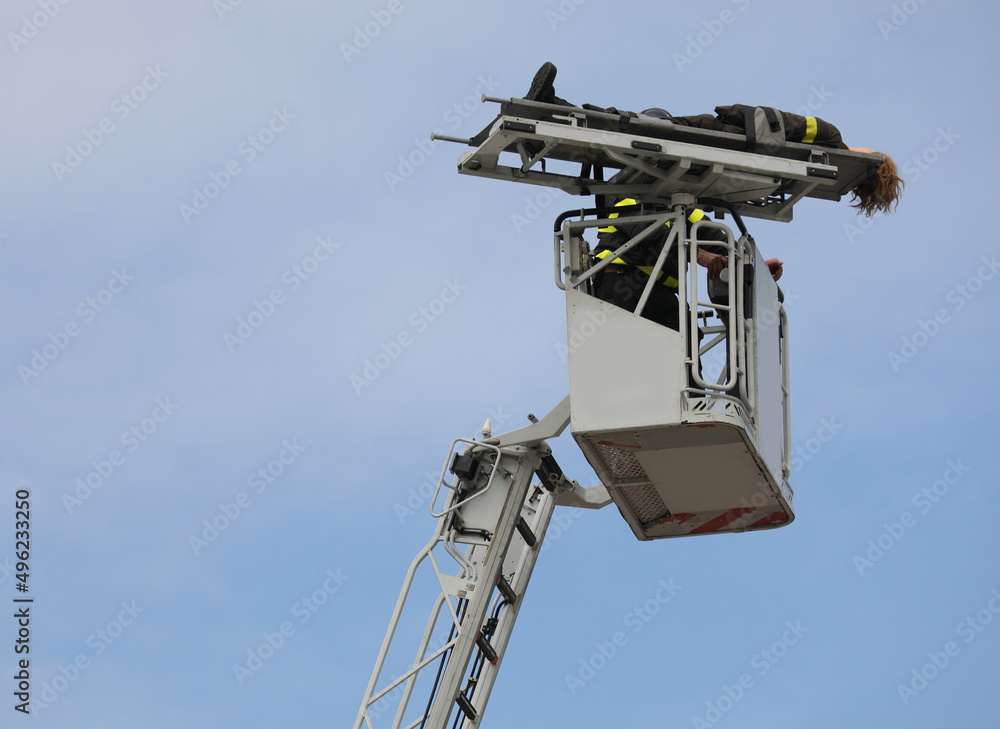 injured person on the stretcher during the rescue of the firefighter on the basket of the ladder truck
