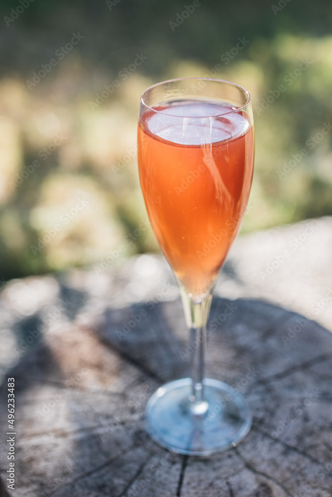 orange wine cocktail drink sitting outdoors on wood stump with green bokeh background orange wine cocktail drink sitting outdoors on wood stump with green bokeh background