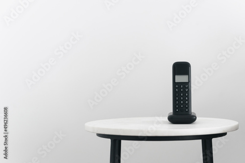 Landline phone standing on small table in room photo