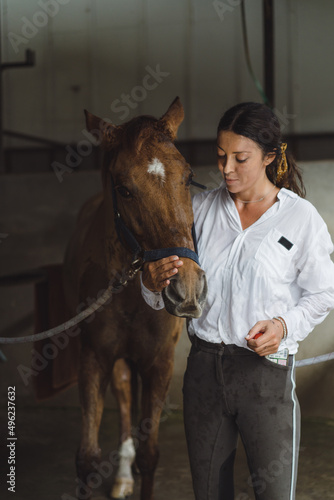 A young woman feeds carrots to a horse.