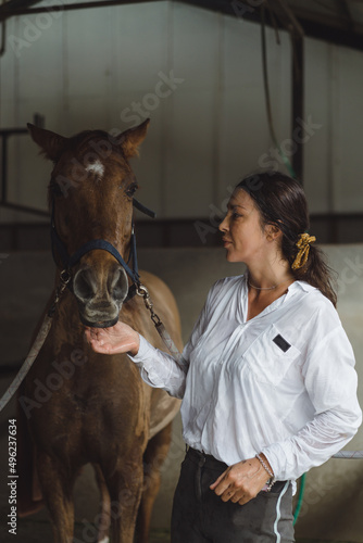 A young woman feeds carrots to a horse. © Yuliya Kirayonak