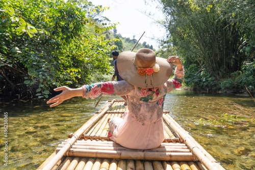 woman sits raft traveling river green forest. 