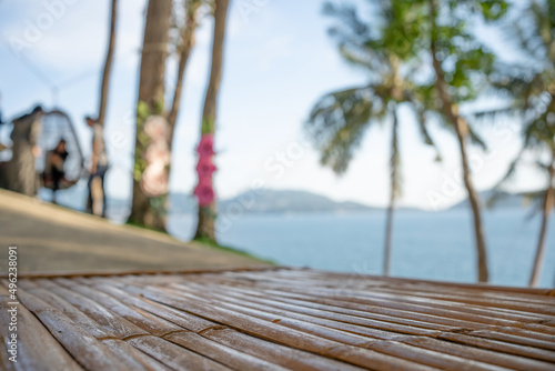 Wooden table top coconut palm trees swings seaside background.